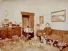 Verkstadsarbetare J. A. Th. Holms fru på 50 årsdagen.
Rumsinteriör, en kvinna.