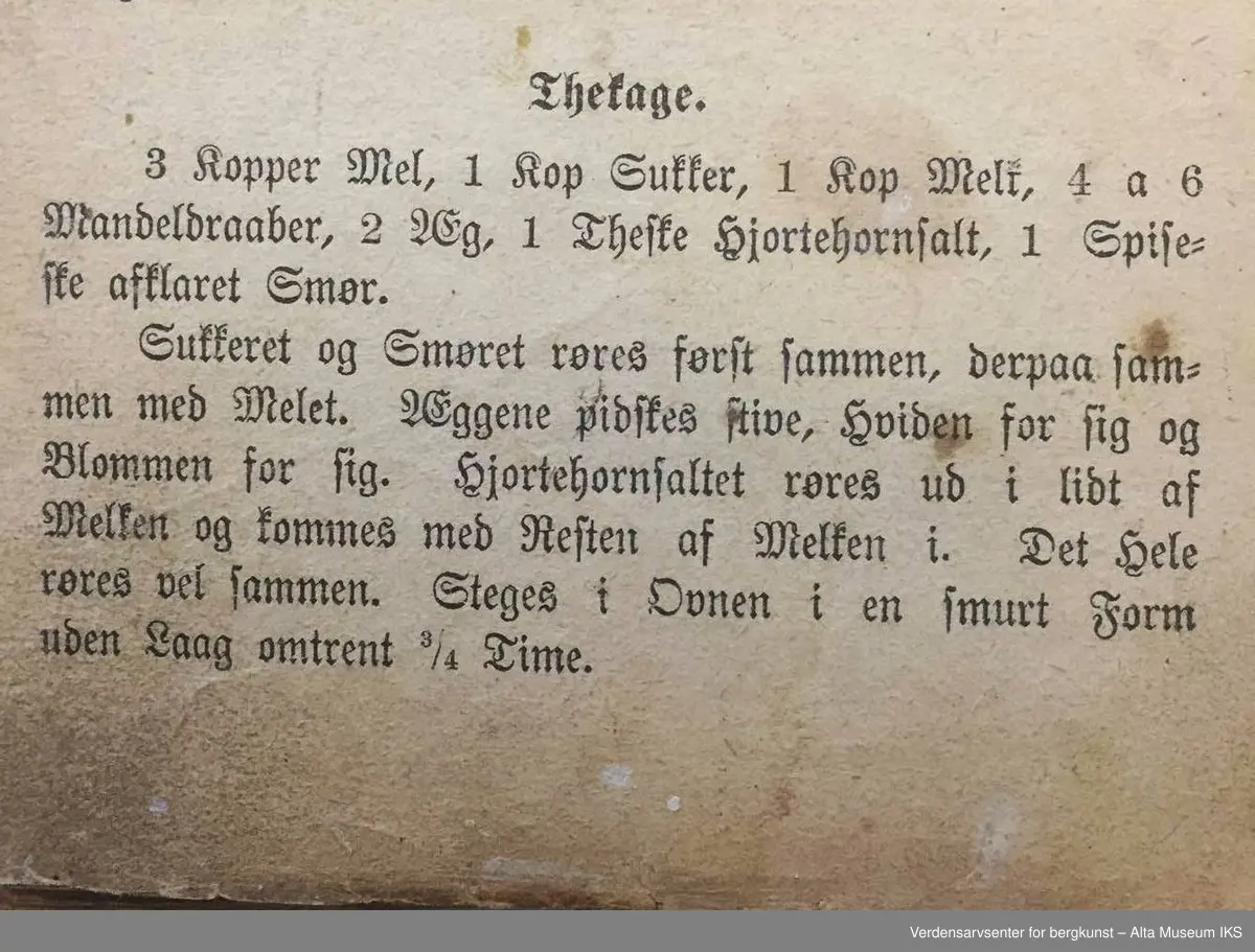Kokebok for tarvelige husholdninger og skolekjøkkener av Antonette Baldjen. Bok med falmet og slitt omslag. Deler av boktittelen kan såvidt skimtes på bokryggen. Mellom to av bokens sider er det en presset firkløver.