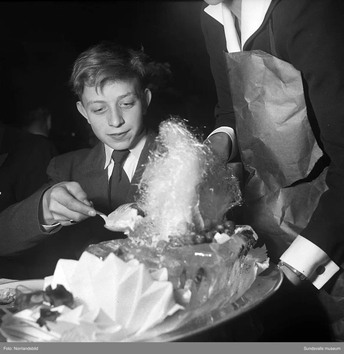 Ett urval av en stor grupp bilder från Lindgrens järnhandels 100-årsjubileumsfest på Knaust. Storstilad entré, mingel, utmärkelser, galamiddag och dans. Underhållning av bland annat en mycket ung Ingeborg Nyberg. På bilderna syns bland annat direktör Fridolf Brunnzell och lagerchefen Carl "Spiken" Lundberg, vilken samma år firade 50 år som anställd vid företaget.