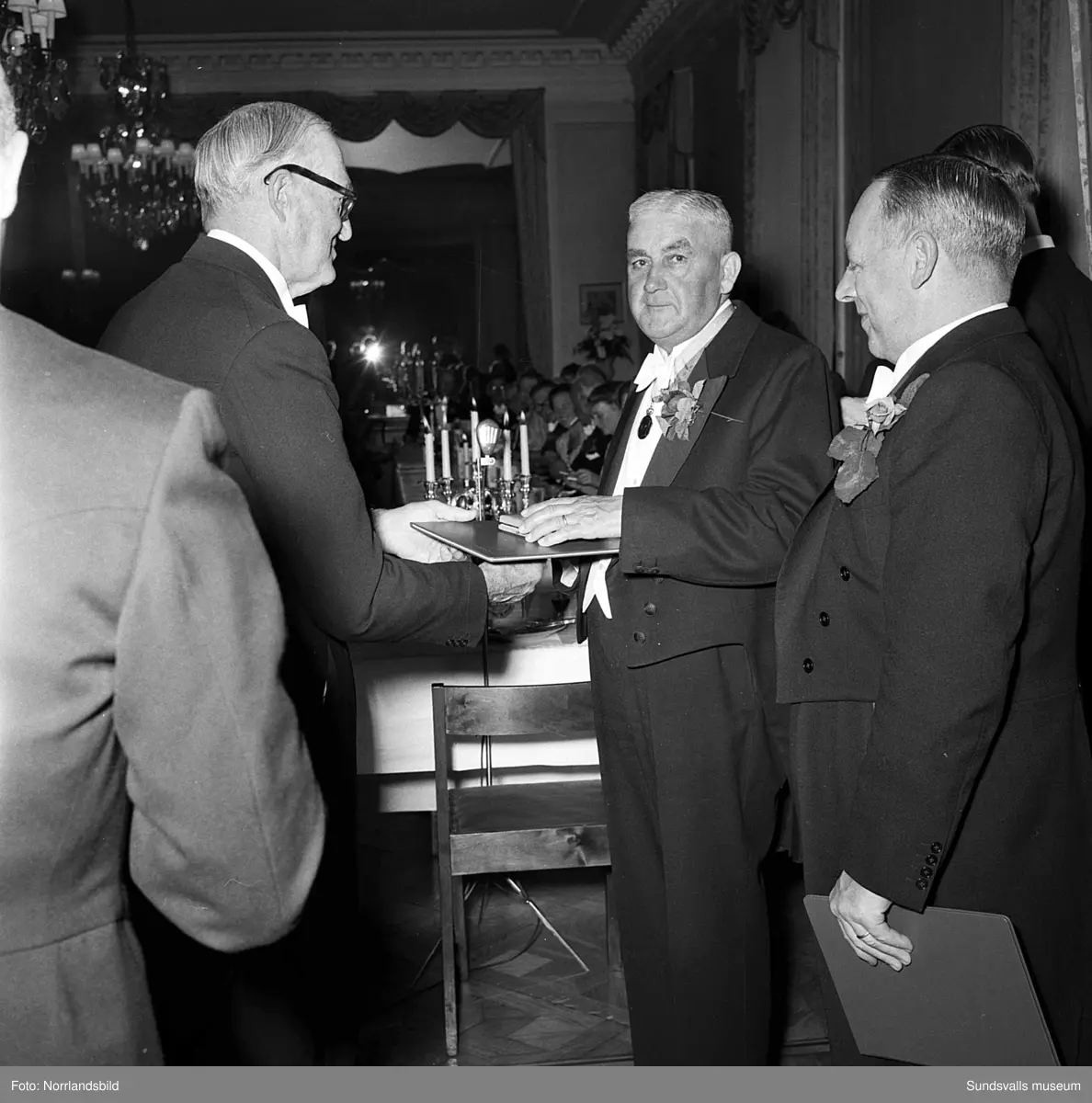 Ett urval av en stor grupp bilder från Lindgrens järnhandels 100-årsjubileumsfest på Knaust. Storstilad entré, mingel, utmärkelser, galamiddag och dans. Underhållning av bland annat en mycket ung Ingeborg Nyberg. På bilderna syns bland annat direktör Fridolf Brunnzell och lagerchefen Carl "Spiken" Lundberg, vilken samma år firade 50 år som anställd vid företaget.