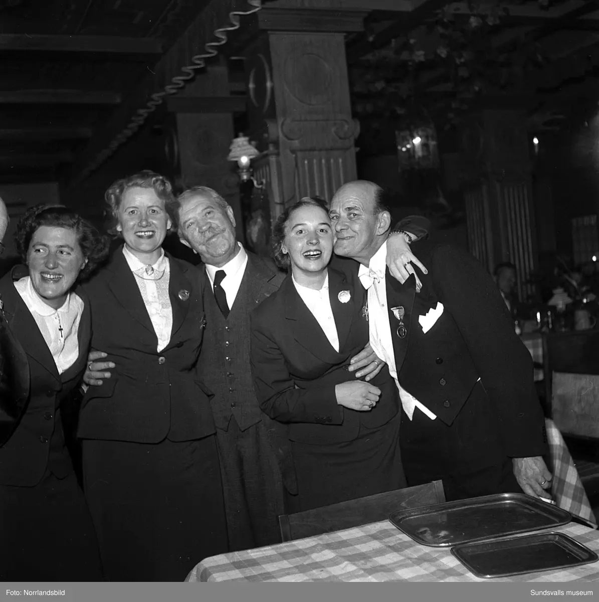 Ett urval av en stor grupp bilder från Lindgrens järnhandels 100-årsjubileumsfest på Knaust. Storstilad entré, mingel, utmärkelser, galamiddag och dans. Underhållning av bland annat en mycket ung Ingeborg Nyberg. På bilderna syns bland annat direktör Fridolf Brunnzell och lagerchefen Carl "Spiken" Lundberg, vilken samma år firade 50 år som anställd vid företaget.