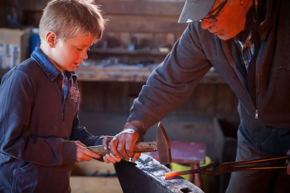 Liten gutt er med smeden i ei smie