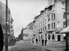 Stenhus i fyra våningar med burspråk och balkonger, affärslokaler i gatuplanet.
Storgatan norrut från Fredsgatan.
Repro 1934 efter en äldre bild.