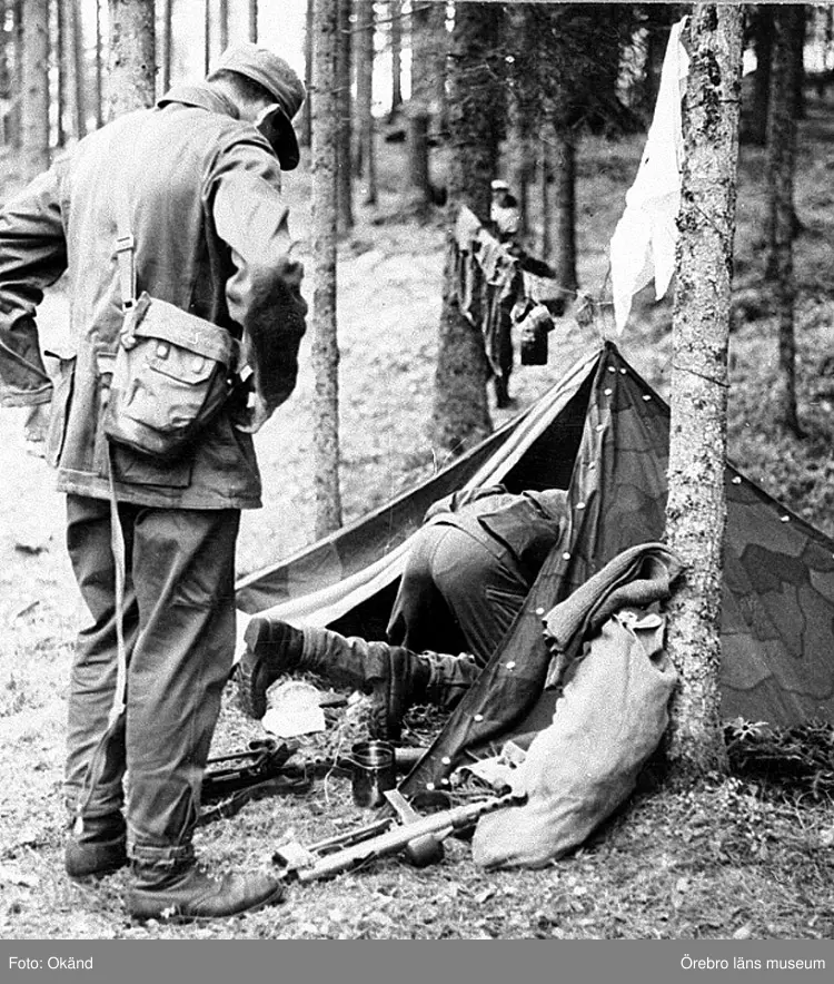 Värnpliktiga ur I3 på 1970-talet med uniform modell 1959 går in i knäppetältet som här består av två delar vilka medfördes i fältutrustningen.
