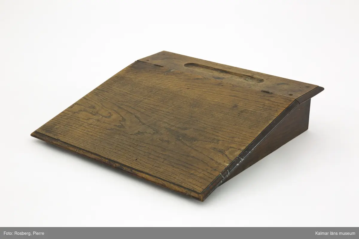 KLM 31942. Pulpet, bordspulpet. Av trä, ek med fanér. Bordspulpet med sluttande, uppfällbart lock samt överst ett fack för pennor och penslar. Pulpeten har legat på skrivbordet KLM 31941.