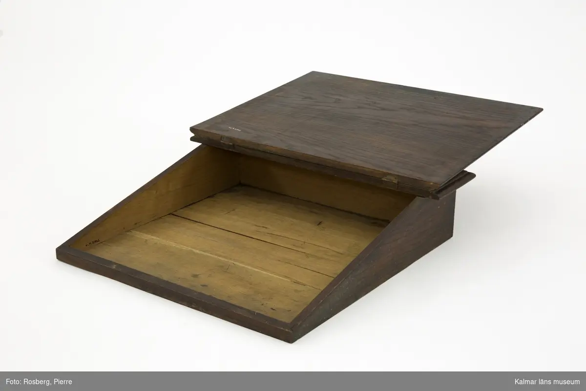 KLM 31942. Pulpet, bordspulpet. Av trä, ek med fanér. Bordspulpet med sluttande, uppfällbart lock samt överst ett fack för pennor och penslar. Pulpeten har legat på skrivbordet KLM 31941.