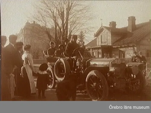 Från bilfärden, bilen märkt T1, framför "Gamla hemmet". Huvudkontoret i bakgrunden. 
Bilen på bilden är en Frayer-Miller från ca 1909, utrustad med en 4-cylindrig luftkyld motor. Den hade registreringsnummer T1 och ägdes av Pontus Lindström från Örebro.