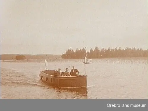 Tre personer i båten "Bylgia".
I bakgrunden "kärleksudden" vid Granliden, Tisaren.