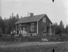 Bostadshus, familjegrupp tre personer framför huset.