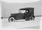 En kvinna vid en bil.
Hjälmaren den 17 februari. 
Bilen på bilden är en Gray Touring från 1922. Den ser ut att vara ny vid fototillfället eftersom den har en temporär registreringsskylt (interimsskylt).