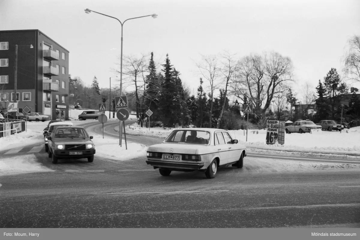 Trafik i korsningen Gamla Riksvägen-Streteredsvägen i Kållered, år 1984.

Fotografi taget av Harry Moum, HUM, Mölndals-Posten, vecka 4, år 1984.

Bildtext:
"Trafik och parkering i Kållereds centrum är ett stort problem. Man måste hålla tungan rätt i munnen och titta åt alla håll. Säkert önskar många Kålleredsbor lite ordning i all oreda.
Snart hoppas man komma gång med en utredning om trafiksituationen."