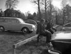 Fyra män. Bostadshus och bilar i bakgrunden.
I väntan på återfärd, Degerfors.
20 maj 1964.