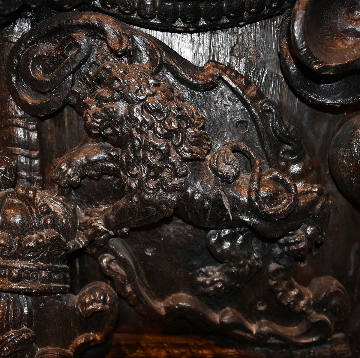 Skulpterad sköld med upprätt, mot höger gående lejon. Lejonet är snidat i hög relief, med heraldiskt stiliserad hållning. Sköldens kontur är rokokomässig, med kanter av varierande bredd och rik pärlbroskdekoration. Upptill avslutas skölden med en ellipsformad broskvolut. Sköldens baksida är slät.

Text in English: Shield with upright, rightward-facing lion. The lion is carved in high relief and reproduced in perspective. It is seen in profile, and its posture is heraldically stylised. The shield has an almost rococo-like outline, with edges of varying width and rich earshell work decorations.The top is finished with an ellipse-shaped pearlwork scroll. The reverse side of the shield is smooth.