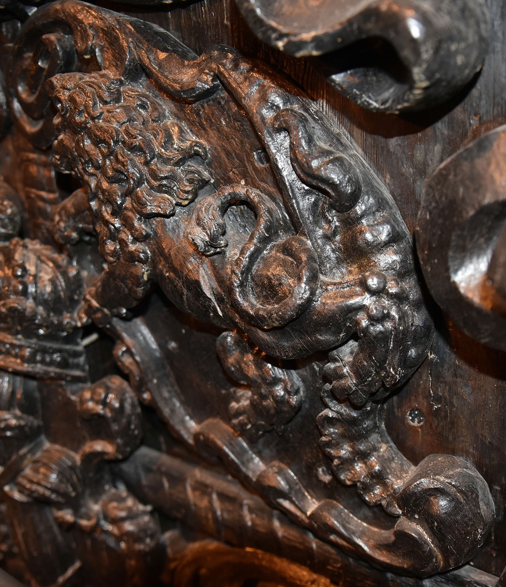 Skulpterad sköld med upprätt, mot höger gående lejon. Lejonet är snidat i hög relief, med heraldiskt stiliserad hållning. Sköldens kontur är rokokomässig, med kanter av varierande bredd och rik pärlbroskdekoration. Upptill avslutas skölden med en ellipsformad broskvolut. Sköldens baksida är slät.

Text in English: Shield with upright, rightward-facing lion. The lion is carved in high relief and reproduced in perspective. It is seen in profile, and its posture is heraldically stylised. The shield has an almost rococo-like outline, with edges of varying width and rich earshell work decorations.The top is finished with an ellipse-shaped pearlwork scroll. The reverse side of the shield is smooth.