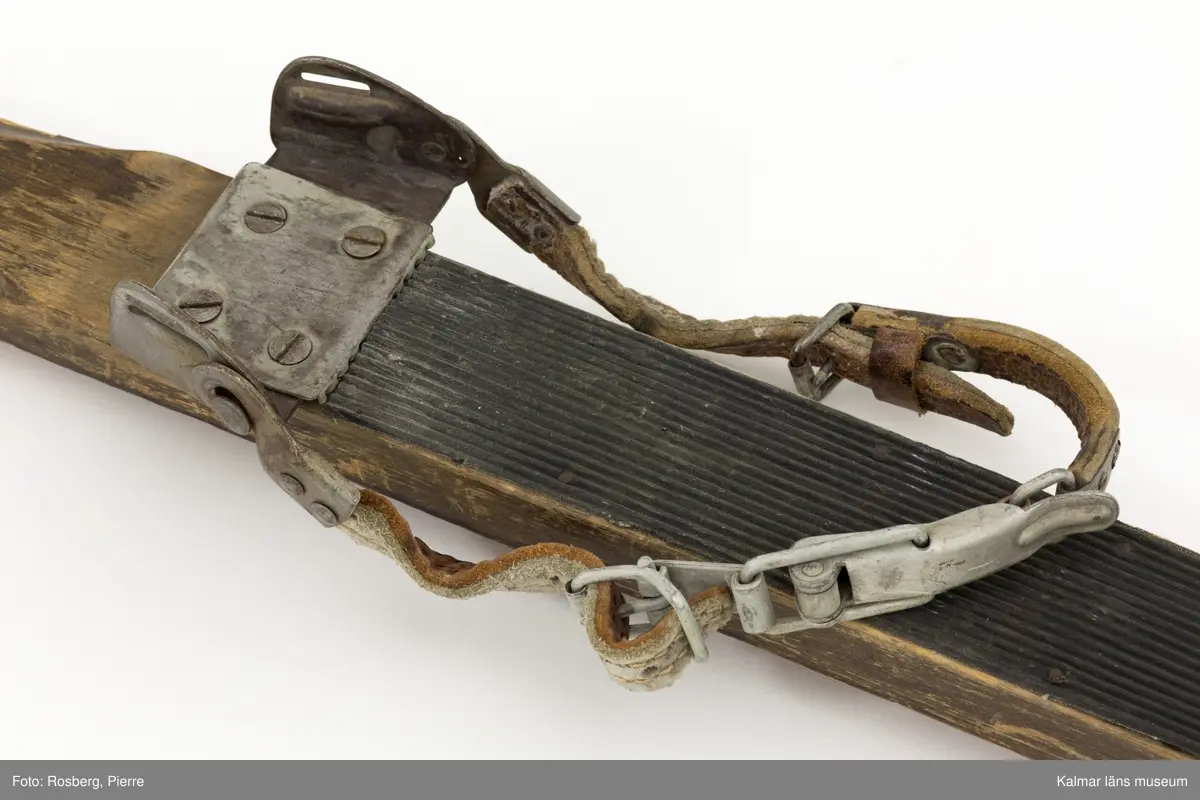 KLM 45692. Skidor, ett par. Av trä, lackade, med gummiklädd fotdel. Bindning av metall med läderremmar. Prägling i metallen: ABC MADE IN SWEDEN PATENT 78242 78489. Prägling i träet: 6 ¼ I 82.