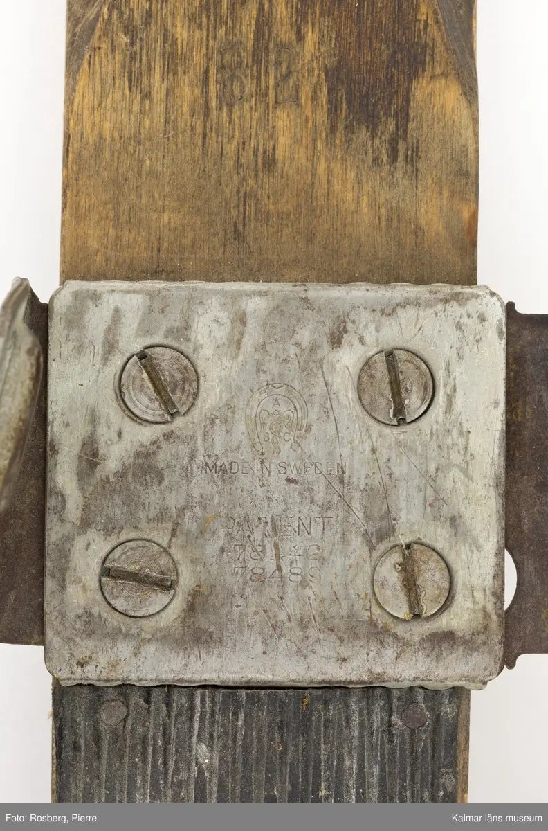 KLM 45692. Skidor, ett par. Av trä, lackade, med gummiklädd fotdel. Bindning av metall med läderremmar. Prägling i metallen: ABC MADE IN SWEDEN PATENT 78242 78489. Prägling i träet: 6 ¼ I 82.
