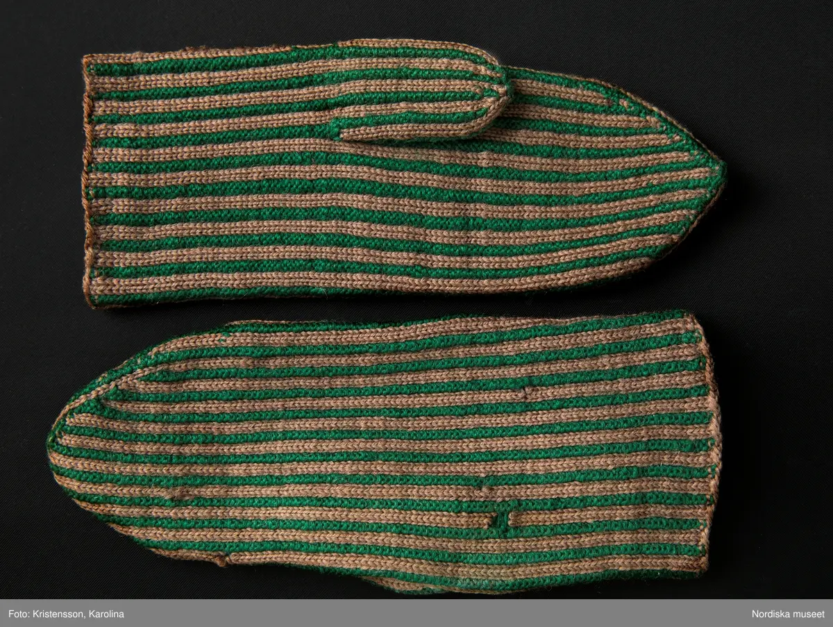 Ett par kvinnovantar stickade av ullgarn, smalrandiga i grönt och ljusbrunt. De ljusbruna ränderna består av 2 maskor slätstickning och de gröna av 2 aviga  maskor,  där de 2 färgerna  hela tiden följer med  och flotterar på avigsidan. Det ger en stum yta utan elasticitet. 
Anm Den högra vanten mer sliten med flera stoppningar med det gröna garnet.
Har tillhört Augusta Davidsson, "Snögges Augusta" f. 1868 i Habo död 1950 på ålderdomshemmet. Hon hade bott hela sitt liv i föräldrahemmet ett soldattorp under Vagnhult i Habo. hennes far var soldat liksom brodern Efraim. Först vårdade hon modern i hemmet, senare hushållade hon åt den ogifte brodern Efraim. Sen gick hon på "hjälpe" hos bönderna i bygden. Foto av stugan skall finnas i museet. Kläderna som museet mottagit är de som hon hade med sig till ålderdomshemmet.
/Berit Eldvik 2013-03-11