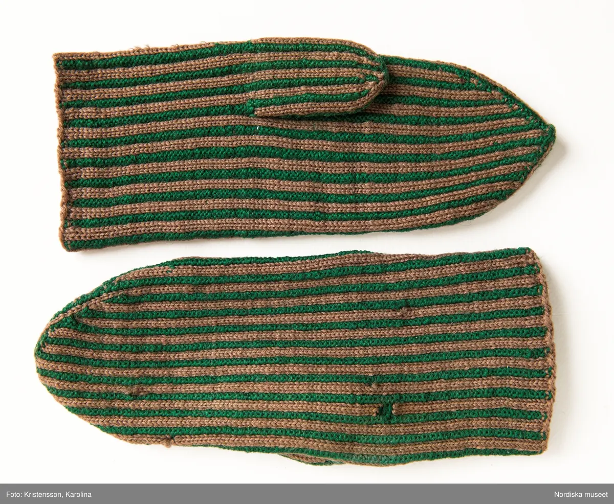 Ett par kvinnovantar stickade av ullgarn, smalrandiga i grönt och ljusbrunt. De ljusbruna ränderna består av 2 maskor slätstickning och de gröna av 2 aviga  maskor,  där de 2 färgerna  hela tiden följer med  och flotterar på avigsidan. Det ger en stum yta utan elasticitet. 
Anm Den högra vanten mer sliten med flera stoppningar med det gröna garnet.
Har tillhört Augusta Davidsson, "Snögges Augusta" f. 1868 i Habo död 1950 på ålderdomshemmet. Hon hade bott hela sitt liv i föräldrahemmet ett soldattorp under Vagnhult i Habo. hennes far var soldat liksom brodern Efraim. Först vårdade hon modern i hemmet, senare hushållade hon åt den ogifte brodern Efraim. Sen gick hon på "hjälpe" hos bönderna i bygden. Foto av stugan skall finnas i museet. Kläderna som museet mottagit är de som hon hade med sig till ålderdomshemmet.
/Berit Eldvik 2013-03-11