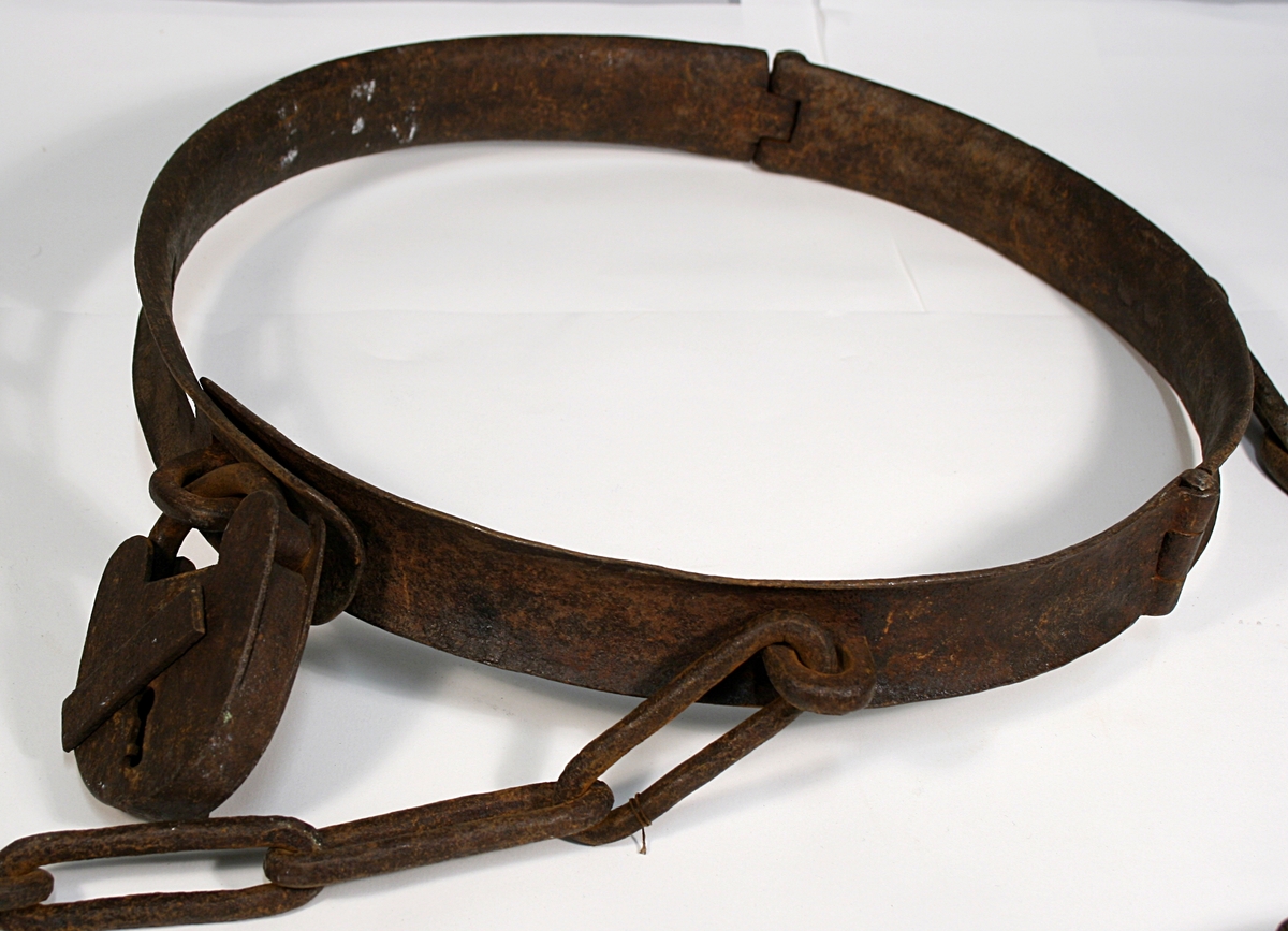 Hals, liv og fotjern festet sammen med lenke. Alle har en hengelås festet.