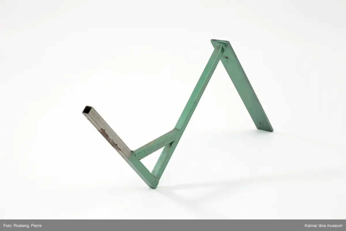 KLM 6304. Hattmakareskylt. Stor rödbrun hatt (s. k. storm) av järnbleck med svart text målad på båda sidor: J.V. Jakobssons ENKA. Tillhörande enkel järnarm för fäste på vägg. Armen är grönlackerad och tillverkad senare, omkring 1995.