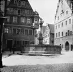 Skioptikonbild med motiv av fontän på torg, bredvid apotek, i Rothenburg.
Bilden har förvarats i kartong märkt: Rothenburg II. 1901.