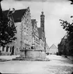 Skioptikonbild med motiv av fontän på torg i Rothenburg, i bakrunden syns tornet på rådhuset.
Bilden har förvarats i kartong märkt: Rothenburg II. 1901.