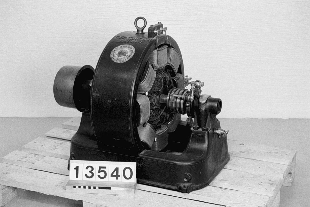 Trefas generator. Skylt: "3 Fasgenerator No 3071 Typ VQ Wenströms Patent 60/105 volt 21 amp. 5 hkr 900 Hvarf 60 per." Ingjutet: "Typ VQ No 3071 Patent" och "Allmänna Svenska Elektriska Aktiebolaget, Vesterås". Komplett. Fordrar 5 hk.