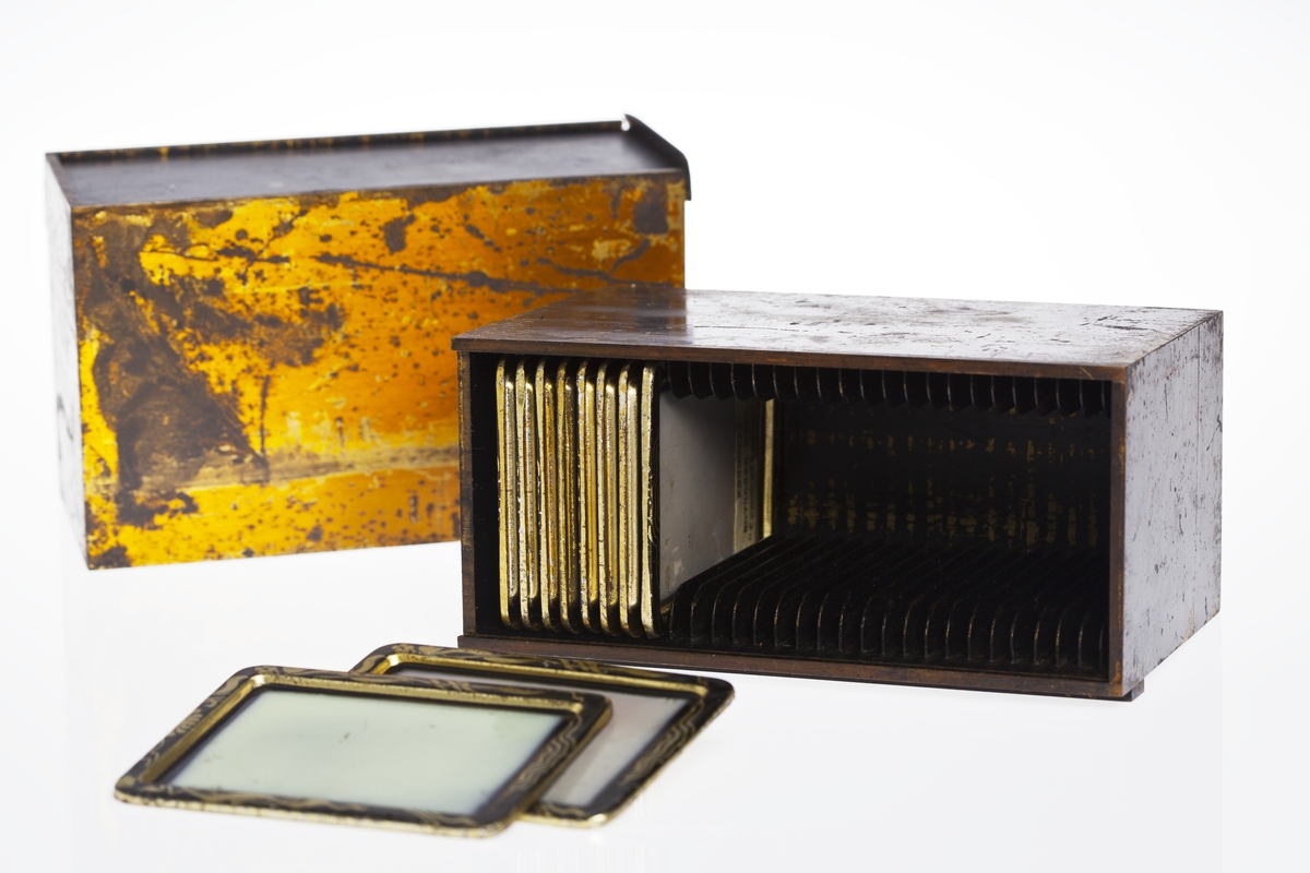 Fotoautomat "Bosco" för tillverkning av ferrotypier. Penningautomat för självfotografering.  Den fungerade på så sätt att det ljuskänsliga skiktet placerats i en profilerad plåtbricka som på samma gång var framkallningsskål och sedan ram för fotografiet. I automaten exponerades bilden i lodrätt läge och framkallades sedan med vätskor som portionerades ur behållare. Efter tre minuter var ferrotypen klar och matades ut ur apparaten. Den behövde torka ytterligare och fick enligt anvisningarna inte utsättas för starkt ljus förrän den var torr. Bilden mätte 60x83 mm och levererades i ett etui av papper. Plåtbrickan hade påtryck av reklam och information på baksida och kanter.
Tillbehör: Sockel med 2 st. metallådor för plåtar, 10 st. plåtar ("W.H.C Bernitt Original Bosco Platte Hamburg 23 ...), överdel med kamera, mekanism, mekanism för framkallning m.m. nyckel till verket.