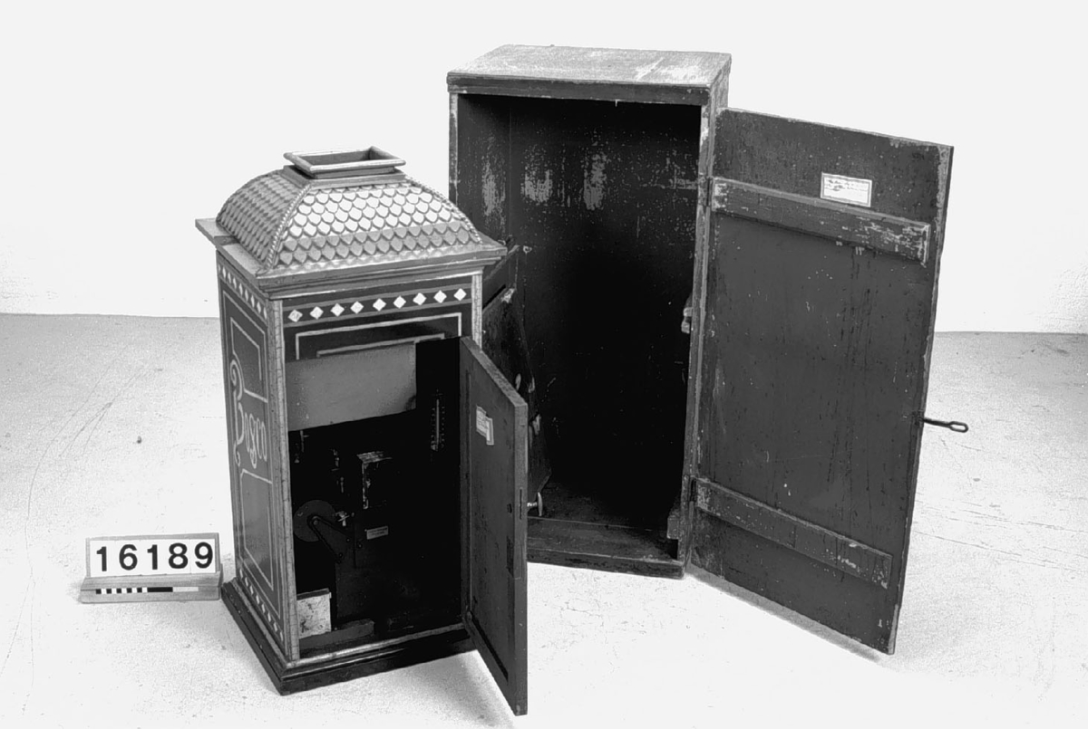 Fotoautomat "Bosco" för tillverkning av ferrotypier. Penningautomat för självfotografering.  Den fungerade på så sätt att det ljuskänsliga skiktet placerats i en profilerad plåtbricka som på samma gång var framkallningsskål och sedan ram för fotografiet. I automaten exponerades bilden i lodrätt läge och framkallades sedan med vätskor som portionerades ur behållare. Efter tre minuter var ferrotypen klar och matades ut ur apparaten. Den behövde torka ytterligare och fick enligt anvisningarna inte utsättas för starkt ljus förrän den var torr. Bilden mätte 60x83 mm och levererades i ett etui av papper. Plåtbrickan hade påtryck av reklam och information på baksida och kanter.
Tillbehör: Sockel med 2 st. metallådor för plåtar, 10 st. plåtar ("W.H.C Bernitt Original Bosco Platte Hamburg 23 ...), överdel med kamera, mekanism, mekanism för framkallning m.m. nyckel till verket.