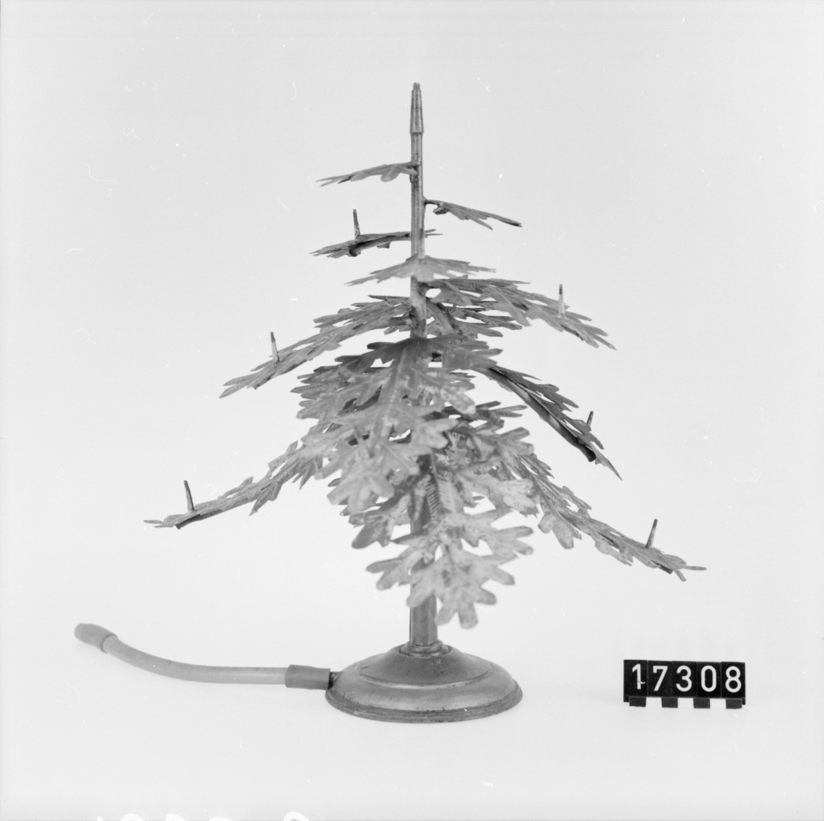 Grönmålad julgran för lysgasanvändning. Tillverkad av förtent bleckplåt med munstycken för gaslågor. Topprydnad (ängel) saknas dock.