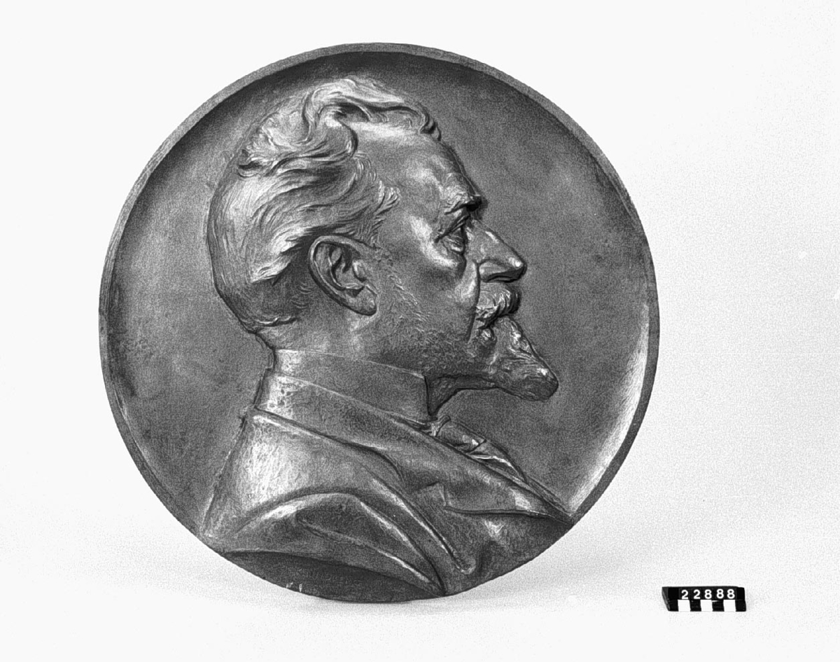 Medaljong i brons, över Knut Agat Wallenberg, f. 1853, d. 1938, höger profil, efter modell, signerad Erik Lindberg.