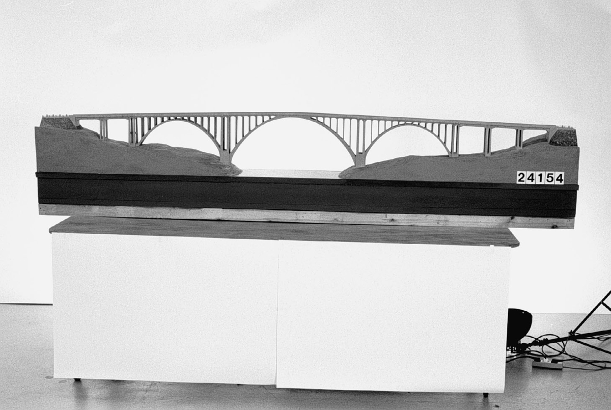 Skalmodell, i målad gips, av Skurubron mellan fastlandet och Värmdö öster om Stockholm, byggd i armerad betong av AB Arcus, Stockholm, åren 1914-16. Bron är 284 m lång med en 72 meter vid båge över farleden. Brobanan är 6,7 m bred och befinner sig 32 m över vattnet.