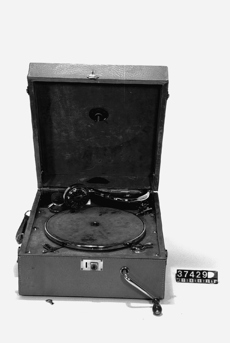 Resegrammofon, med fjäderverk, stiftdosa och hastighetsregulator. Läderklädd väska och förnicklade metalldelar.
Tillbehör: 2 vevar och nyckel.