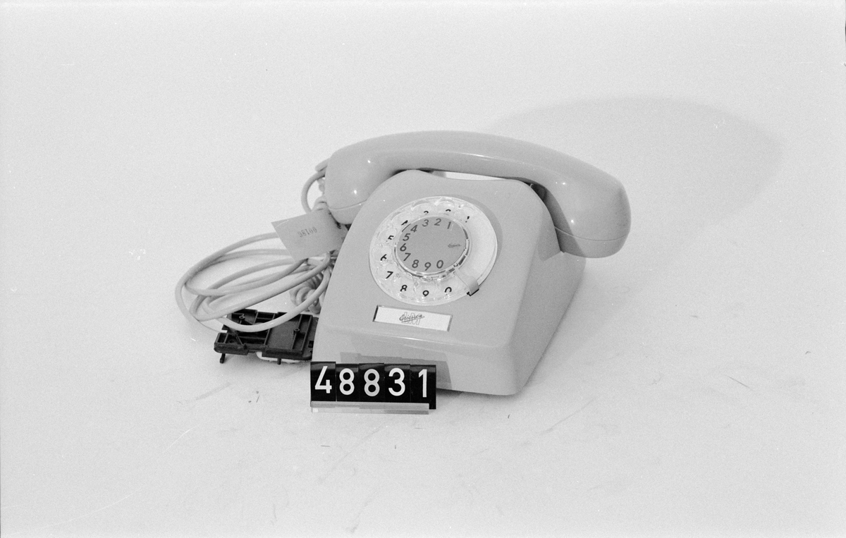Telefonapparat Dialog för AT-system, huvudapparat, anknytningsapparat till växel och sidoapparat. Bordsmodell av termoplast med transparent fingerskiva och apparatsnöre anslutet till väggplint. Att fingerskivans numrering börjar på 1-2-3 och inte 0-1-2 indikerar att telefonen inte är avsedd för den svenska marknaden. Ringsignalens styrka är ställbar med ett reglage på apparatens undersida.