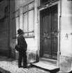 Skioptikonbild med motiv av man som betraktar en dörr till okänd byggnad.
Bilden har förvarats i kartong märkt: ?