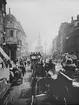 Skioptikonbild med motiv av trafikerad gata i London vid sekelskiftet 1900. Bilden är tagen på Strand vid Waterloo bridge, med St Clement Danes i fonden.
Bilden har förvarats i kartong märkt: ?