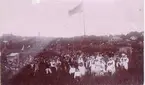 Från Planteringsförbundets sommarfest 1897. I klungan här ovan urskiljs bland annat sedermera borgmästarinnan Tullie Koch, frk. Anna Rehn (senare gift med Paul Elgh), handlare Nils Johansson, fru Forsberg, född Ericsson, kassör J.V. Ander, fröken Edith Anderson, fru Tegnér, född Janzon, kassör Hj. Lundbladh, fru Sigurd Johanson, född Uggla, disponent Oskar Nilsson, veterinär E. Kylén, poliskonstapel Hellström. Brudparet okänt. Det översta vita tornprydda huset i högra övre hörnet är J.A. Forss. Därefter följer hitåt apotekshuset, doktor Neumans (sedan doktor Jungmarkers) snickare Hultings (sedan skrädd.) elektr. Erikssons (sedermera) och till sist häråt under uppbyggnad varande före detta gamla lasarettsbyggnaden 