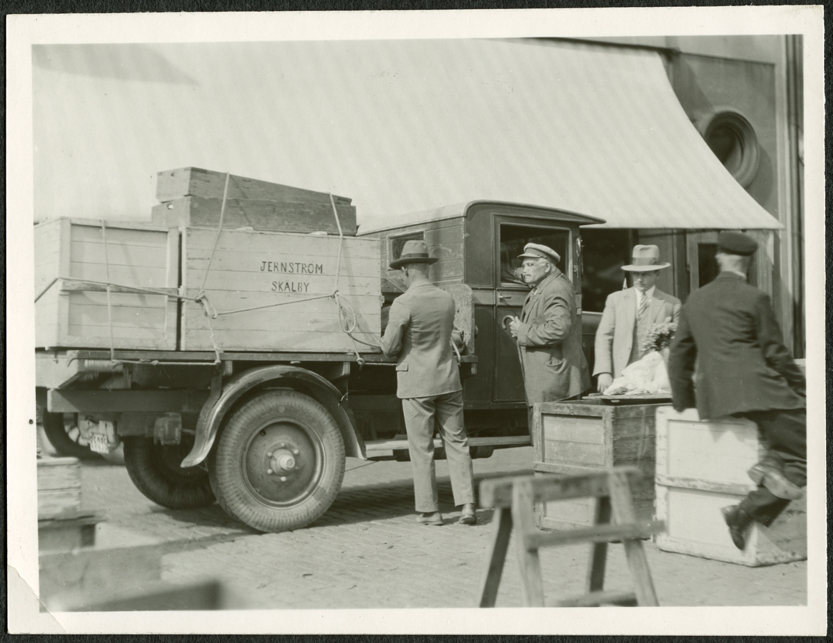 "Hemtransport av tömda lådor".

"Dagligt liv i Sverige 1930"
Dagens Nyheter utlyste en fototävling den 15 juni 1930 för amatörfotografer. Temat var att "i logiskt sammanhängande fotografier ge glimtar av originella eller vardagliga former av svenska folkets liv, i helg och söcken." Förebild för tävlingsbidragen var den kända bildsidan "Fotografen berättar" i Dagens Nyheters söndagsbilaga. Antalet fotografier i varje serie skulle vara minst 10, högst 12.
Som prisnämnd fungerade två av tidningens medarbetare samt docent John Herzberg på KTH, tillika känd fotograf.

Läkaren och hängivne amatörfotografen E D Schött i Stockholm gick ut på Hötorget en vacker augustidag.