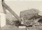 Halmpress kombinerad med tröskverk från Bröderna Anderssons Gjuteri, Skåne. Denna press såld 1910, var ännu i användning 1926. Flickan slår knuten på halmbalarna.