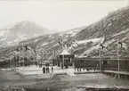 Från Riksgränsbanans byggnation: Riksgränsens station, dekorerad med svenska och norska flaggorna i topp vid invigningen den 14 juli 1903. Invigningståget med kung Oscar lämnar stationen för att fortsätta till Narvik.