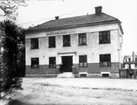 Skaraborgs Enskilda Bank, Floby. Byggt 1923. På trappan kamrer Artur Nilsson och i porten hans barn Åke och Lillan. T.h. syns hotell Gästis.