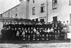 J.A Forss Hattfabrik AB. Fabrikör J.A. Forss med sin personal omkr. 1900. J. A. Forss fabrikspersonal vid tillbyggnaden. 1. Einar Blom, 2. Lars Johansson, 3. Hjalmar Jakobsson, 4. Ole Halvorsén, 5. Gustaf Holmberg, 6. J. A. Forss, 7. Ackerman, 8. Paul Fritsche, 9. Karl Asplund, 10. Hilda Hagman, 11. Grönlund, 12. Sven Nilsson (Kvarnen), 13. Axel Karlsson. Namnuppgifter: Greta Lundström, Högarensgatan 9 A, kontorist i firman. Gunnar Jakobsson, Idrottsgatan 19, lagerchef i firman.