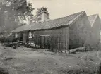 Wallanders bagarstuga t.v. Gården kallades Wallanderska gården men tillhörde Frans Eriksson. Gränsade till Storgatan 7-9. Revs 1911. Nils Janssons gård och magasin t.h. Sedan 1928 Sparbankens fastighet.