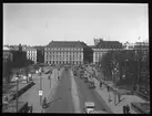 Skioptikonbild från Institutionen för fotografi vid Kungliga Tekniska Högskolan. Använd av professor Helmer Bäckström som föreläsningsmaterial. Bäckström var Sveriges första professor i fotografi vid Kungliga Tekniska Högskolan i Stockholm 1948-1958.
Tre bilder tagna från samma punkt (från Slottsbacken mot Gustav Adolfs torg, Stockholm).  Denna bild är tagen med optik med brännvidden 18 cm. Jämför SKC6355 och SKC6357.
För mer info se: Bäckström, Helmer. Fotografisk Handbok. Natur och Kultur. Stockholm. 1942. s. 58.