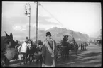 Skioptikonbild från institutionen för fotografi vid Kungliga Tekniska Högskolan. Bilden är troligen tagen av John Hertzberg under en resa i Europa. Hertzberg blev docent i fotografi 1921vid Kungliga Tekniska Högskolan i Stockholm. Kvinna tillsammas med hästar som utfodras