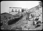 Skioptikonbild från institutionen för fotografi vid Kungliga Tekniska Högskolan. Bilden är troligen tagen av John Hertzberg under en resa i Europa. Hertzberg blev docent i fotografi 1921vid Kungliga Tekniska Högskolan i Stockholm. Hus med vattenbrunn.