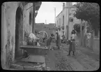 Skioptikonbild från institutionen för fotografi vid Kungliga Tekniska Högskolan. Bilden är troligen tagen av John Hertzberg under en resa i Europa. Hertzberg blev docent i fotografi 1921vid Kungliga Tekniska Högskolan i Stockholm. Kvinnor tvättar utomhus.