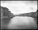 Skioptikonbild från institutionen för fotografi vid Kungliga Tekniska Högskolan. Vy från Ponte Vechio (Den gamla bron) över floden Arno i staden Florens, Italien. Bilden är troligen tagen av John Hertzberg under en resa i Europa.