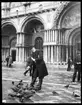 Skioptikonbild från institutionen för fotografi vid Kungliga Tekniska Högskolan. Motiv från San Marcusplatsen i Venedig. John Hertzberg matar duvor. Bilden är  tagen i anslutning till en av John Hertzbergs resor i Europa.