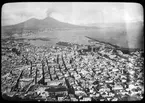 Skioptikonbild från institutionen för fotografi vid Kungliga Tekniska Högskolan. Motiv föreställande Neapelbukten med Vesuvius i bakgrunden, Italien. Bilden är troligen tagen av John Hertzberg under en resa i Europa..